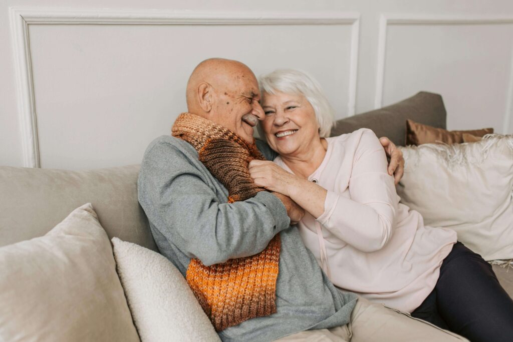 two older people on a couch hugging